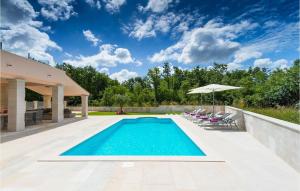 a swimming pool in a backyard with chairs and an umbrella at Villa Liv in Pula