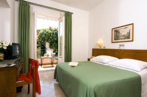 a bedroom with a green bed and a window at Hotel Villa Angelica in Ischia
