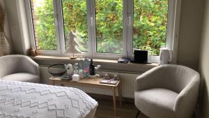 1 Schlafzimmer mit 2 Stühlen, 1 Bett und 2 Fenstern in der Unterkunft The Cozy Cottage in Eeklo