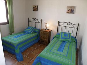 two twin beds in a room with a night stand at Villa Marta Clara in Conil de la Frontera +9 photos