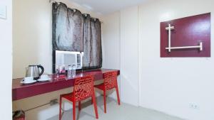 a red desk with two red chairs in a room at RedDoorz at DBuilders Rooms Ph2 Taguig in Manila +24 photos