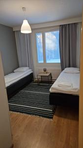 Una pequeña habitación con dos camas y una ventana. en Uitontie Apartment, en Kajaani