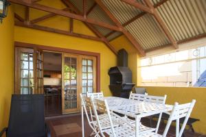 a patio with a table and chairs and a grill at Red Mountain House in Clarens