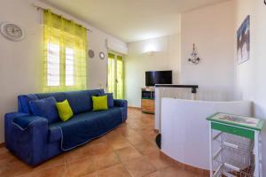 un salon avec un canapé bleu et une télévision dans l'établissement La Casa Al Mare, à Castelsardo