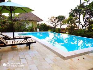 una piscina con banco y sombrilla en Villa Anaïs Jardin Paradisiaque Face à la Mer, en Banjar 12 fotos más