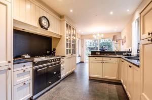 eine große Küche mit weißen Schränken und einer Uhr an der Wand in der Unterkunft The Cozy Cottage in Eeklo