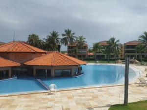 a large blue swimming pool with palm trees and buildings at Resort Aquaville Apartmento in Aquiraz