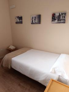a white bed in a room with pictures on the wall at Apartamento Barbadillo - Redmansur in Cáceres
