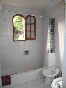 baño con bañera, aseo y ventana en Hostel de Los Artistas en Mendoza
