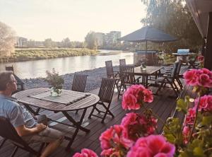 a man sitting at a table next to a river at Villa Venetsia tilava huvila in Lapua