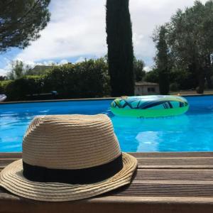 a straw hat sitting on a bench next to a swimming pool at le domaine des cyprès location gite piscine à Bédoin, Mont-Ventoux in Bédoin +7 photos