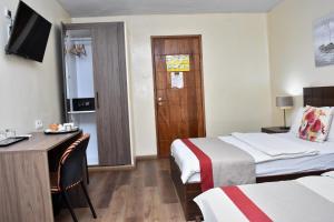a hotel room with two beds and a desk and a door at Hotel du Plateau in Dakar