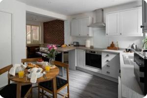 a kitchen with white cabinets and a table with food on it at Classy 2 bed-sleeps 4-king& twin rooms-free parking-close to town & beach in Exmouth