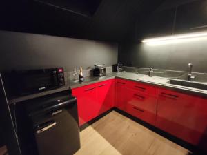 a red kitchen with a sink and a microwave at La Love room in Arbois