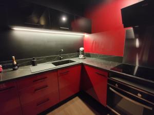 a red kitchen with a sink and red cabinets at La Love room in Arbois +12 photos