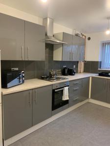 a kitchen with stainless steel appliances and gray cabinets at Campion Contractor Stays With Parking in Sheffield