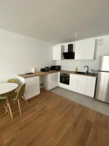 a kitchen with white cabinets and a table and a sink at Appartement cosy, proche transports Paris in Chevilly-Larue