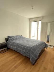 a large bed in a white room with a wooden floor at Appartement cosy, proche transports Paris in Chevilly-Larue