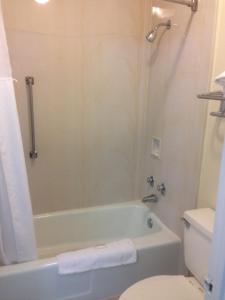 a bathroom with a bath tub and a toilet at Rodeway Inn & Suites Greensboro Southeast in Greensboro