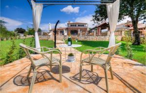 een patio met 2 stoelen en een tafel met een fles wijn bij Villa Oxalis in Poreč