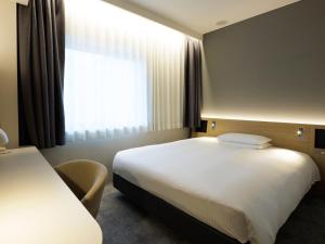 a hotel room with a bed and a window at Hotel Nikko Narita in Narita