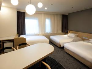 a hotel room with two beds and a table at Hotel Nikko Narita in Narita