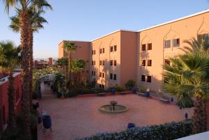 a courtyard in a building with palm trees and a fountain at Kenzi Azghor in Ouarzazate