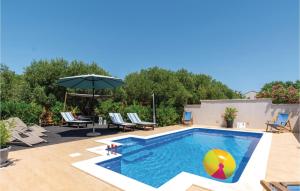 a pool with chairs and an umbrella on a patio at Luxurious Home In Lumbarda With Sauna in Lumbarda