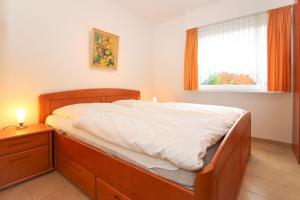 1 dormitorio con cama con marco de madera y ventana en Bungalow-Cara, en Norddeich