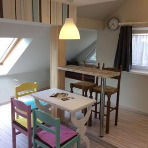 a dining room with a table and chairs and a clock at Báró Berg Apartman in Kapuvár +8 photos