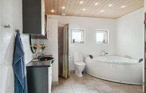a bathroom with a tub and a toilet and a sink at Holiday Home Sivsangervej Ebeltoft Iii in Øksenmølle
