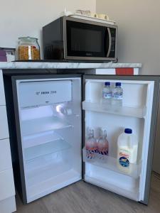 an open refrigerator with bottles of water and a microwave at Caversham B&B in Perth