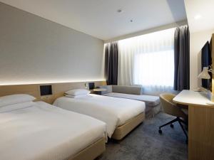 a hotel room with two beds and a desk at Hotel Nikko Narita in Narita