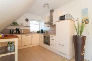 a kitchen with white cabinets and a microwave on top at FriesenZeit in Norden