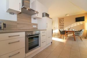 a kitchen with white cabinets and a table with chairs at FriesenZeit in Norden