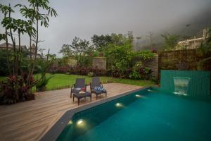 two chairs sitting next to a swimming pool at SaffronStays Rockford Manor in Āmbavna