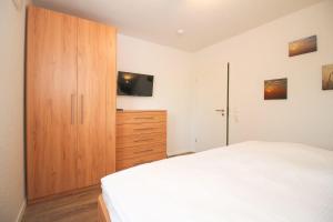 Un dormitorio con una cama blanca y un armario de madera. en Friesenstrasse, en Norden