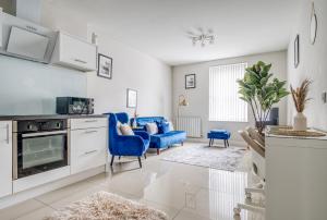 a kitchen with blue chairs and a living room at Blue Horizon 1-Bedroom Apartment Near Hospital in Cardiff