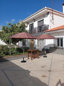 a picnic table and two umbrellas in front of a building at Villa Turística Miguel in Pulianas