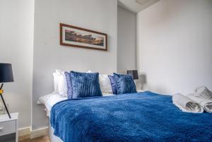 a bedroom with a blue bed with blue pillows at Blue Horizon 1-Bedroom Apartment Near Hospital in Cardiff