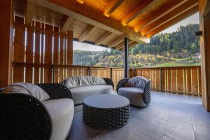 サンタ・クリスティーナ・ヴァルガルデーナにあるChalet Urela Luxury Apartmentのソファ、テーブル、椅子が備わるポーチ