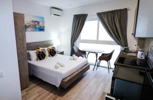 Napoli Suites Studios Aparthotel في سانت جوليانز: غرفة نوم بها سرير ومكتب وتلفزيون