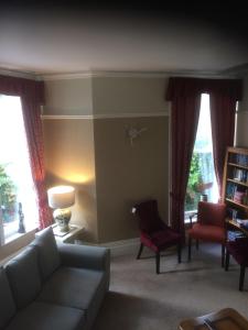 a living room with a couch and chairs and windows at The Brandize Guest House in Torquay