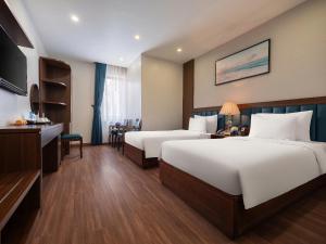a hotel room with two beds and a desk at Halong Boutique Hotel in Ha Long