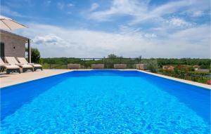 a large blue swimming pool with chairs and an umbrella at Villa Marika in Lašći