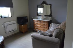 B&B Hof Ter Haegen في Vollezele: غرفة معيشة مع كرسي وخزانة ومرآة