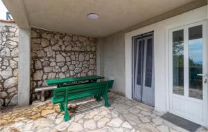 a green bench sitting on a porch next to a stone wall at 2 Bedroom Cozy Apartment In Jadranovo in Jadranovo +18 photos