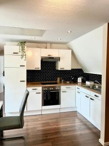 a kitchen with white cabinets and a chair in it at Airport Business Apartment in Norderstedt