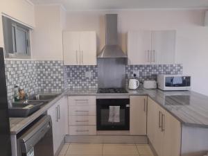 a kitchen with white cabinets and a stove top oven at City Sanctuary Trift Towers in Windhoek