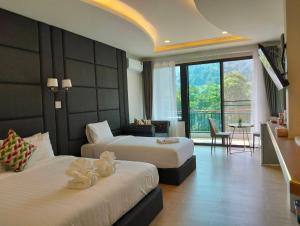 a hotel room with two beds and a living room at Kiree River Hotel โรงแรมคิรีริเวอร์ in Ban Thong Pha Phum